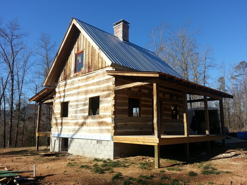 Log cabin with metal roof in forest clearing