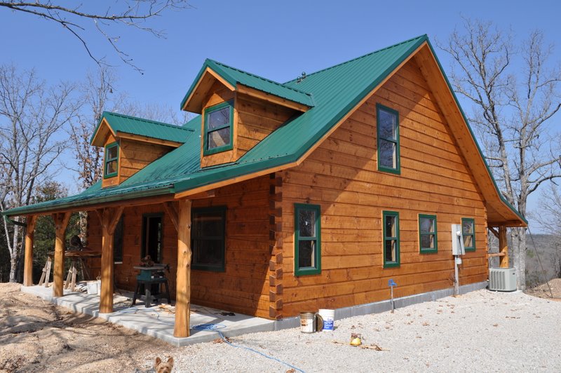 Rustic wooden cabin with green roof in the countryside.