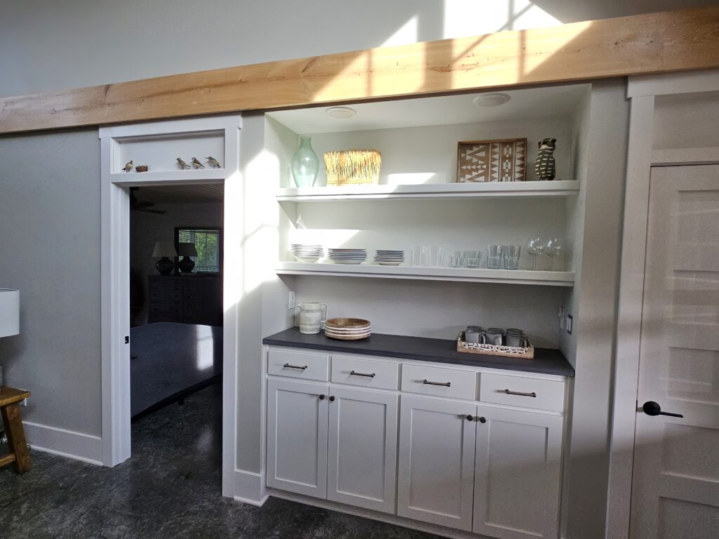 Modern kitchen nook with open shelving and sunlight.