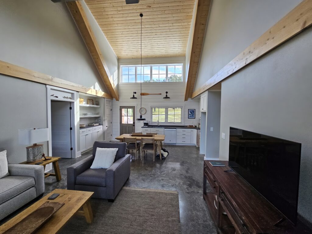 Modern spacious living room with vaulted ceiling and kitchen.