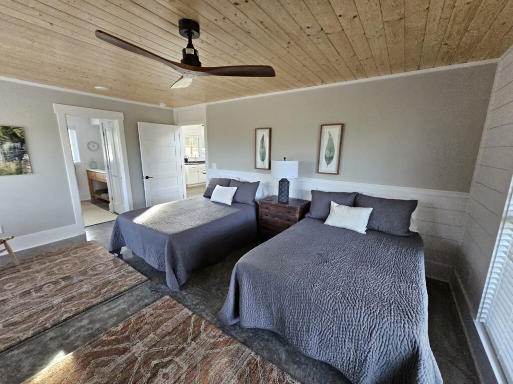 Twin beds in modern bedroom with ceiling fan.