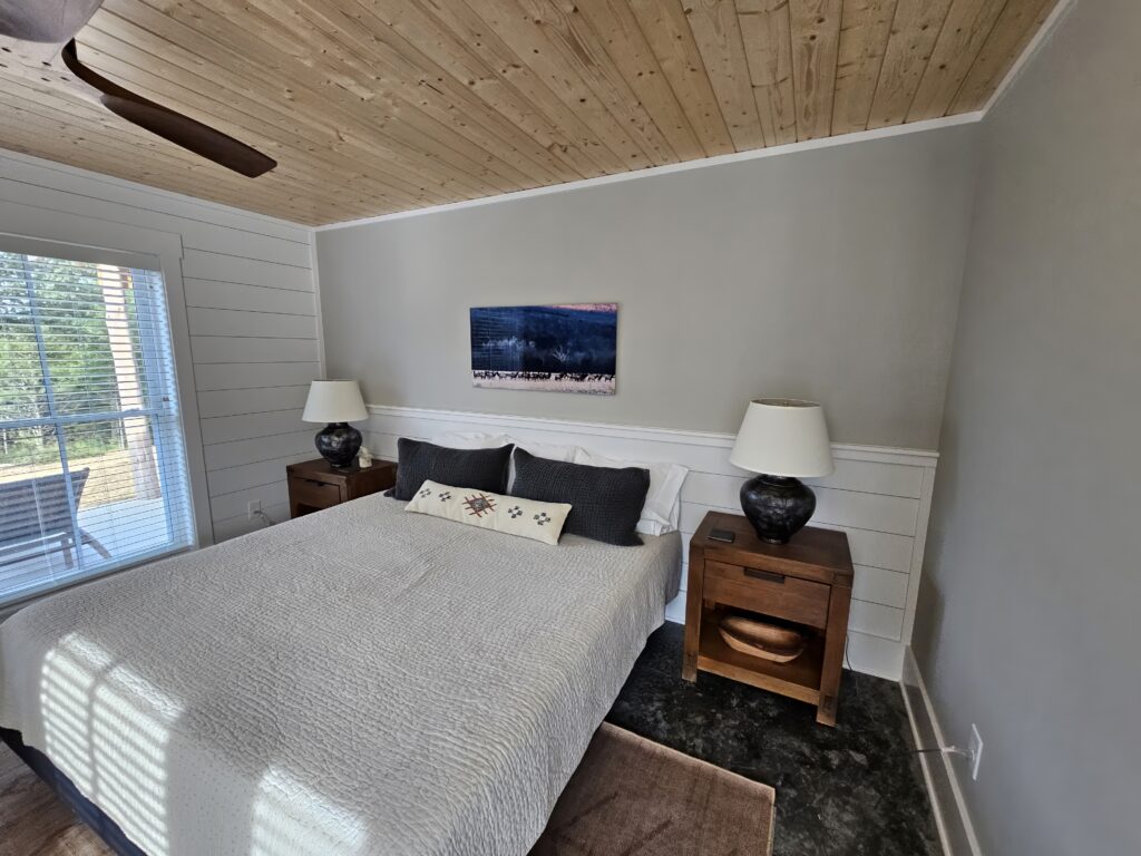 Cozy modern bedroom with wooden ceiling and natural light.