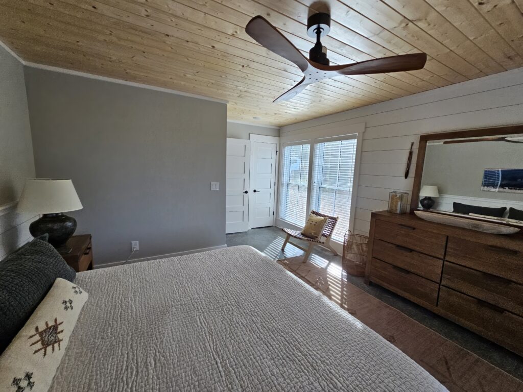 Cozy bedroom with wooden ceiling, furniture, and natural light.