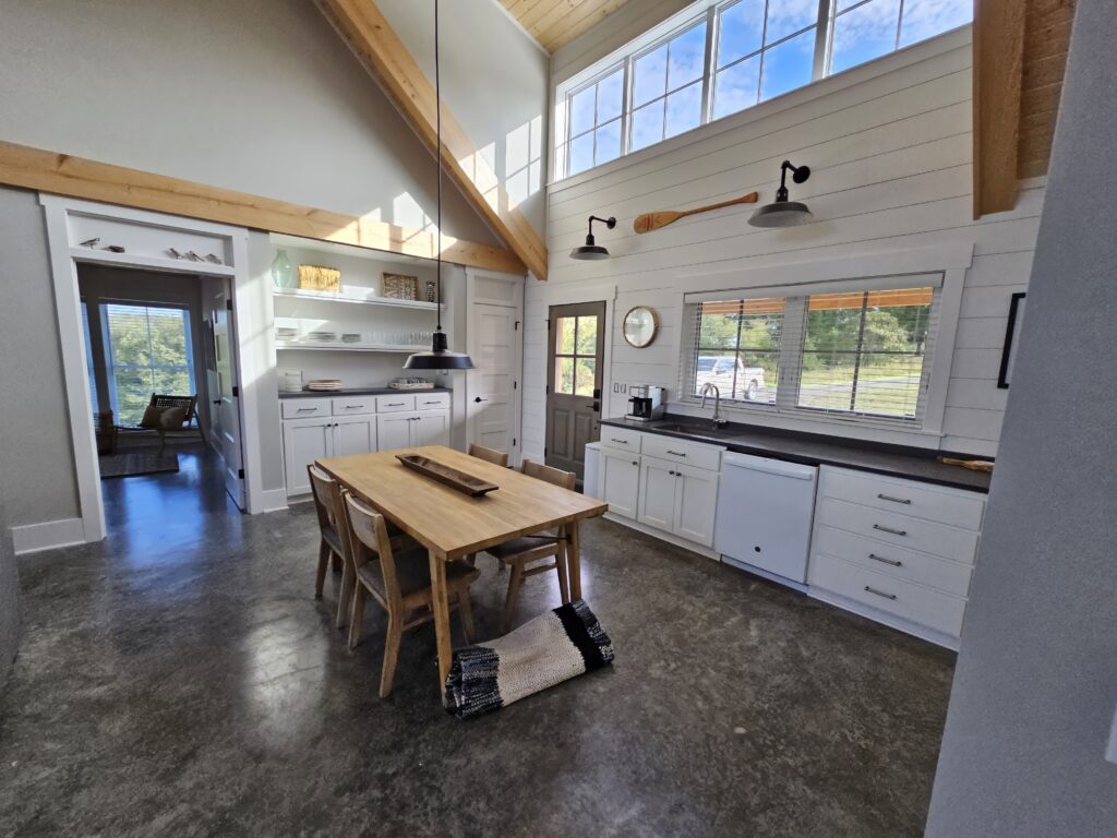 Modern kitchen with high ceilings and wooden dining table.