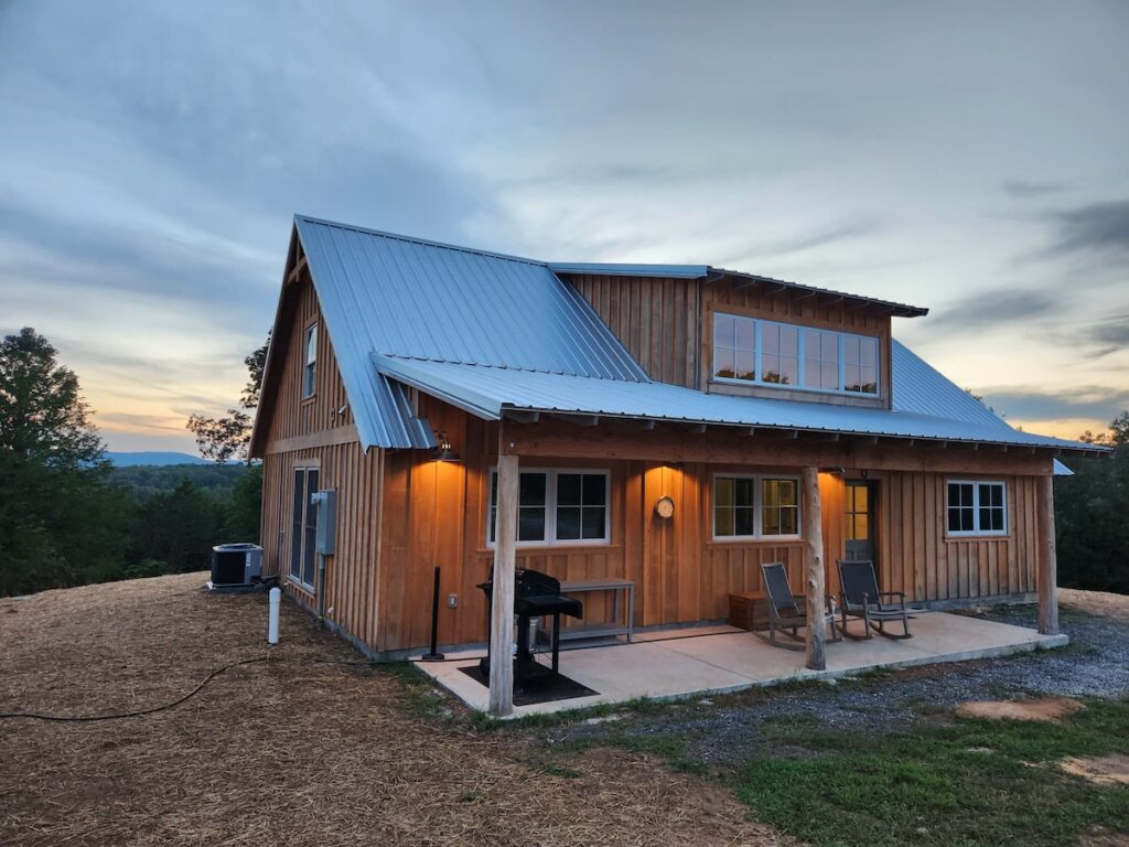 Wooden cabin at dusk with mountain view.