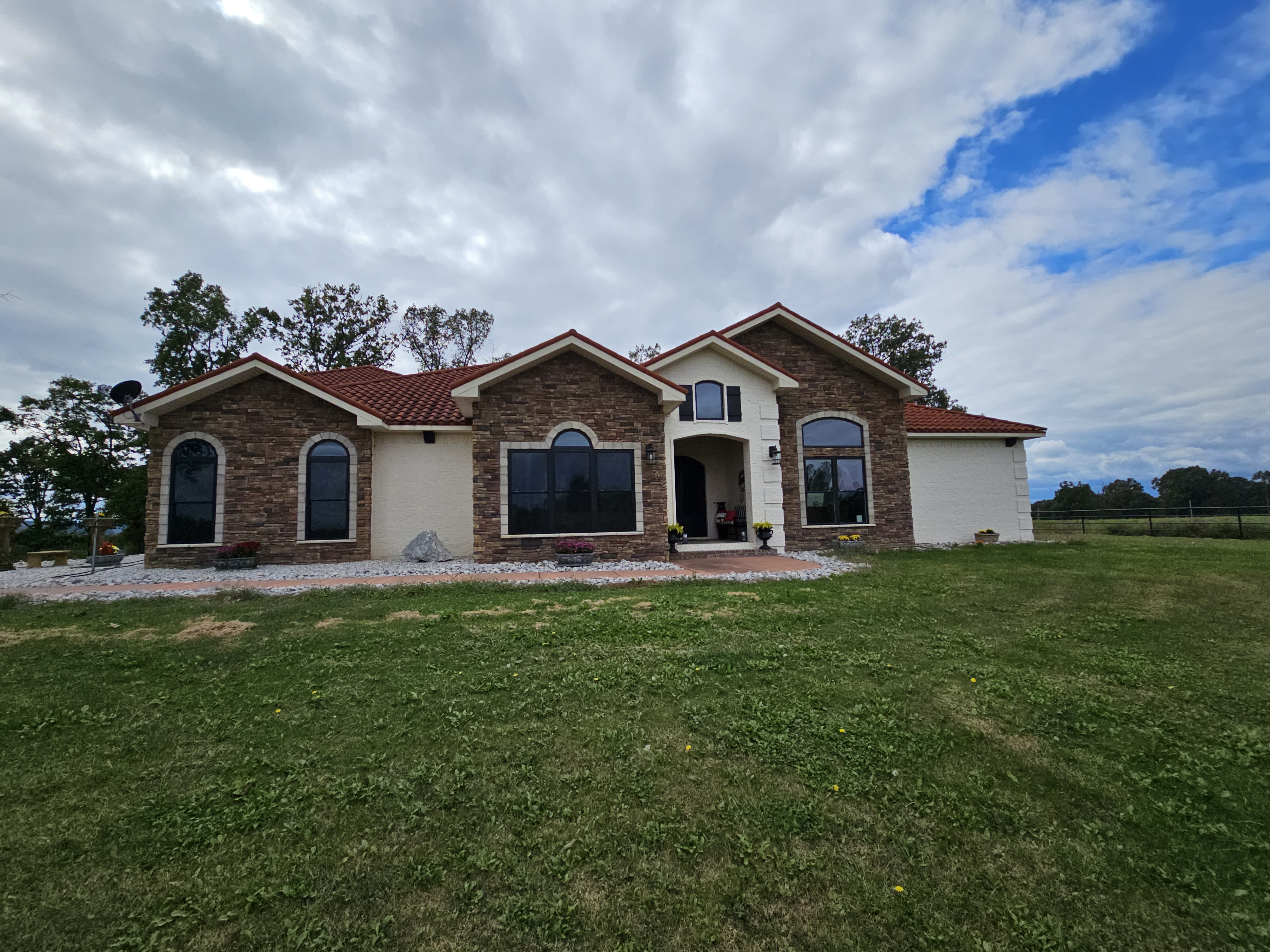 Spacious suburban home with stone facade and red tile roof.