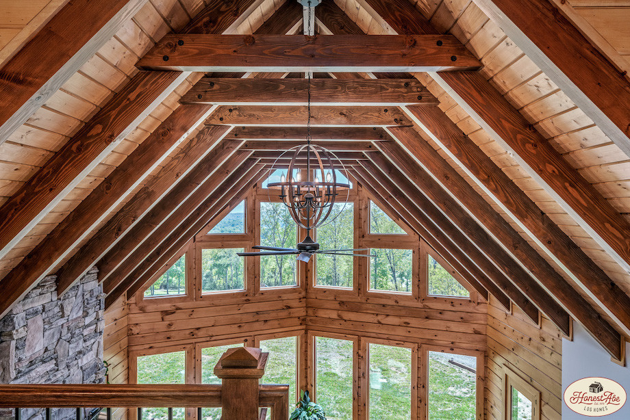 Rustic wooden cabin interior with large windows and chandelier.