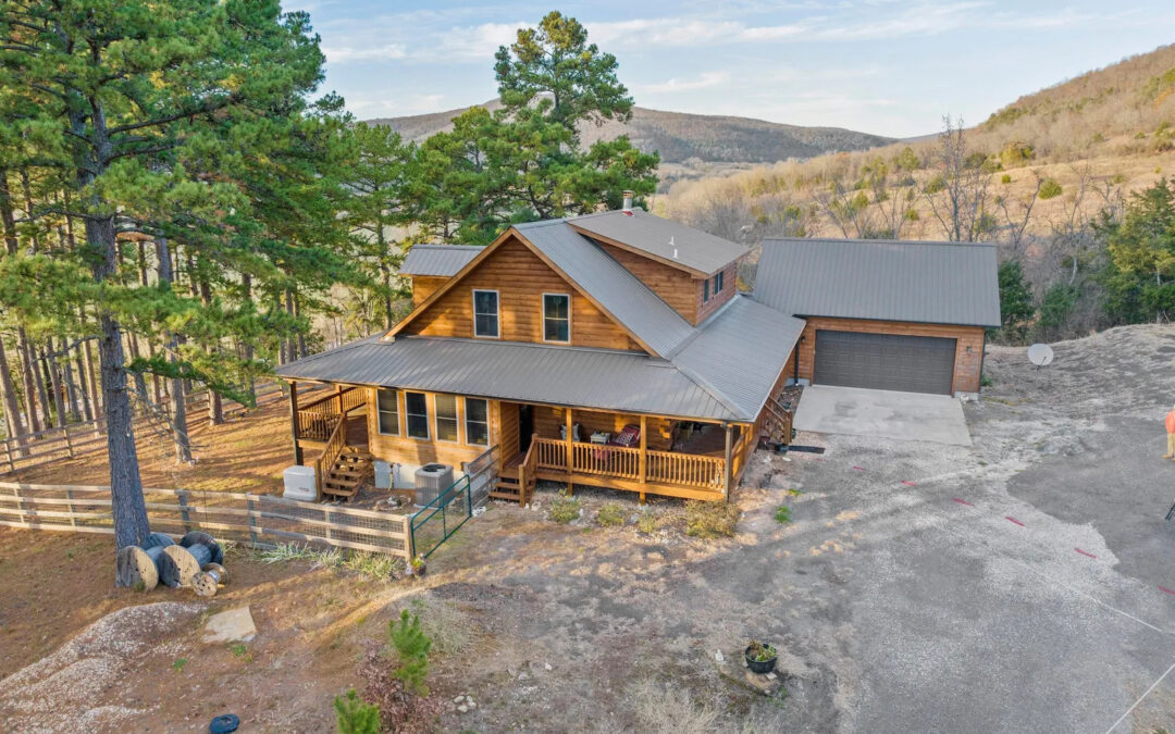 Wooden cabin with garage in forested mountain area.