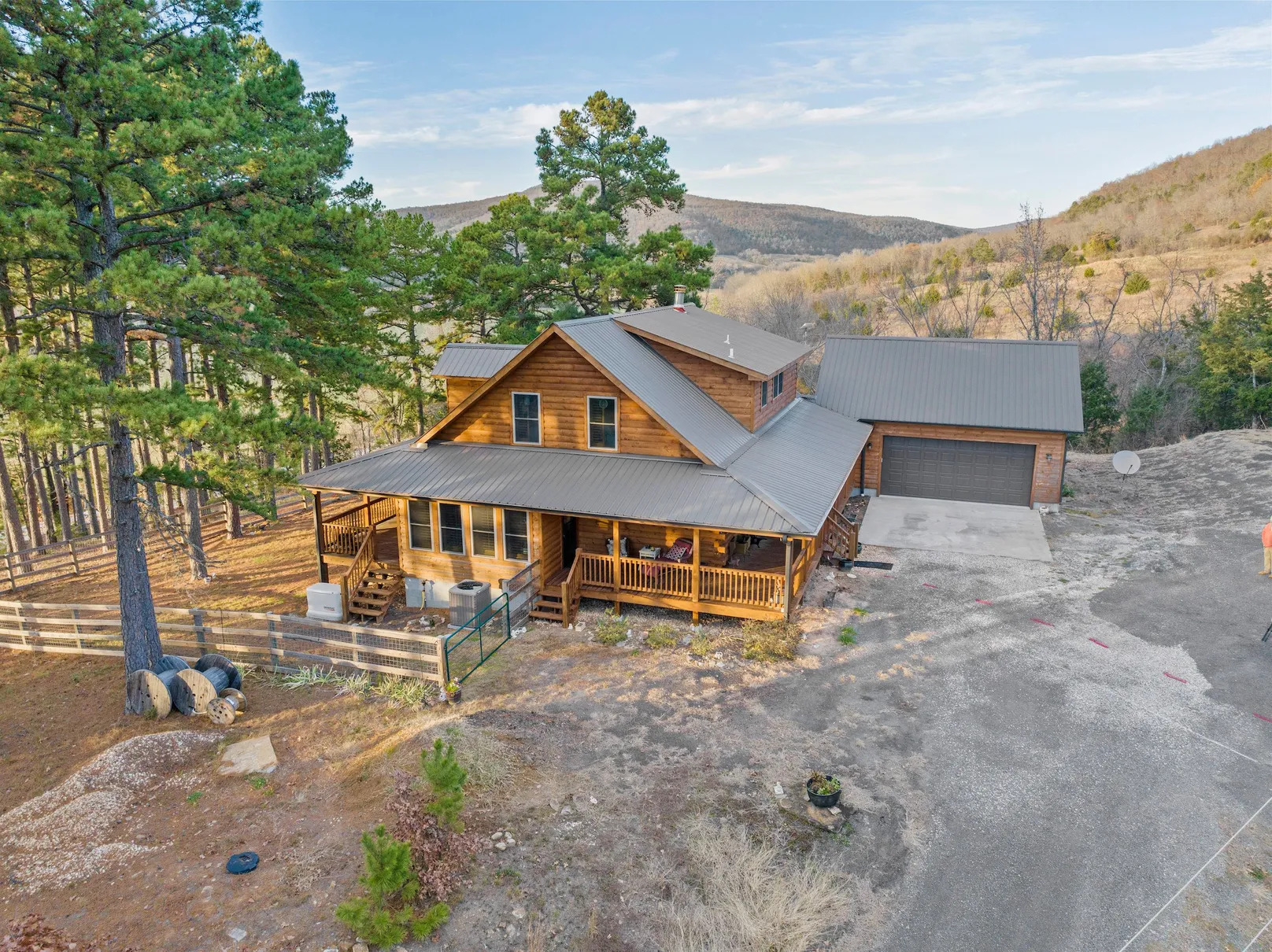 Wooden cabin with garage in forested mountain area.