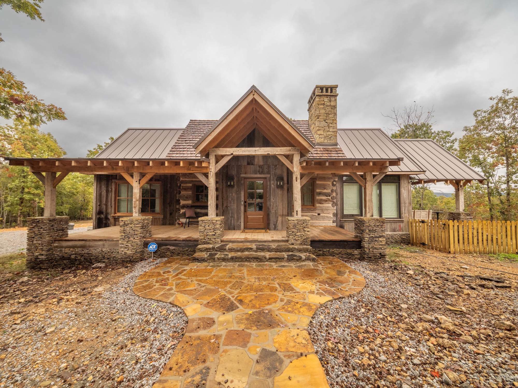 Wooden cabin with garage in forested mountain area.