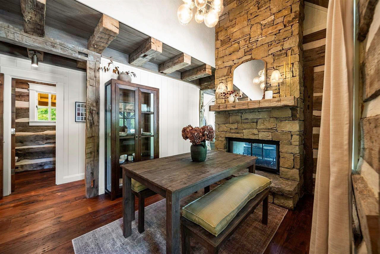 Dining and sitting area with stone fireplace and exposed historic logs