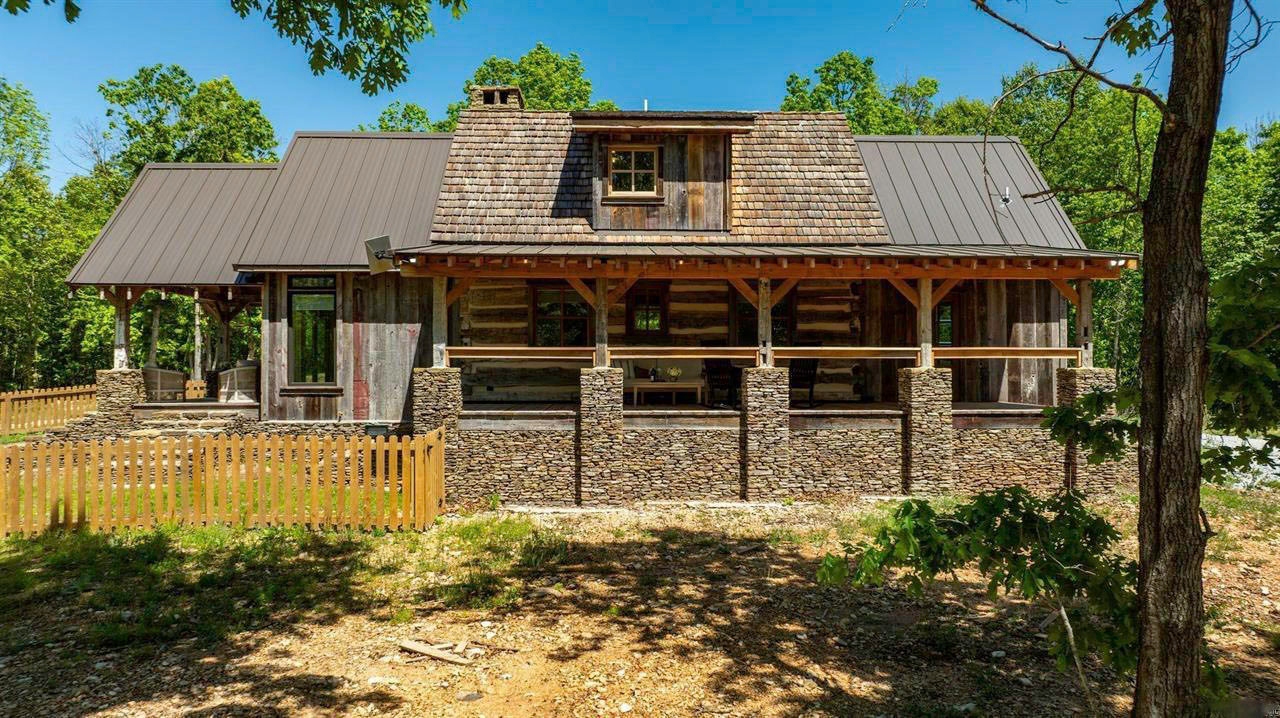 Exterior side view of the restored historic log cabin with stone foundation and timber porch