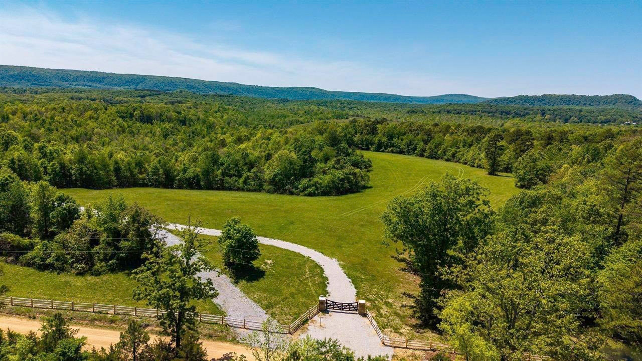 Aerial view of the cabin setting among open fields and wooded Ozark hills